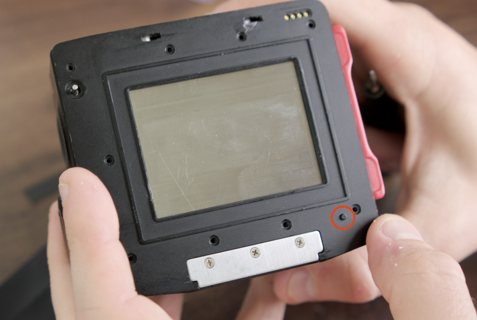 Front panel still on the film back with the small darkslide-release peg circled near the bottom-right corner.