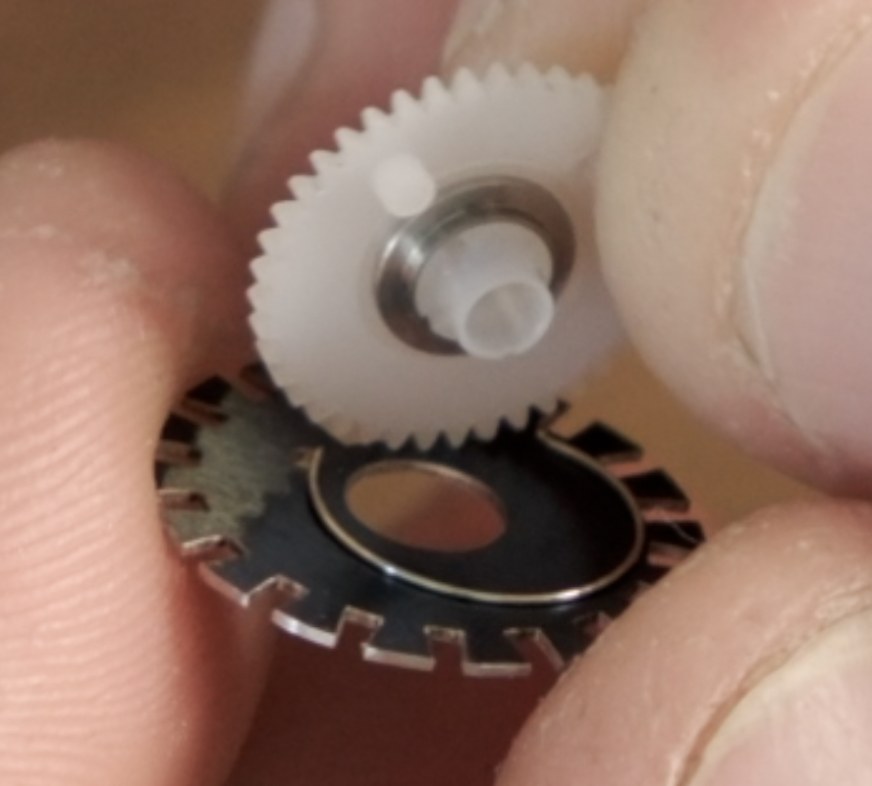 White gear tab aligned with the wire spring and arc slot on the new disc.