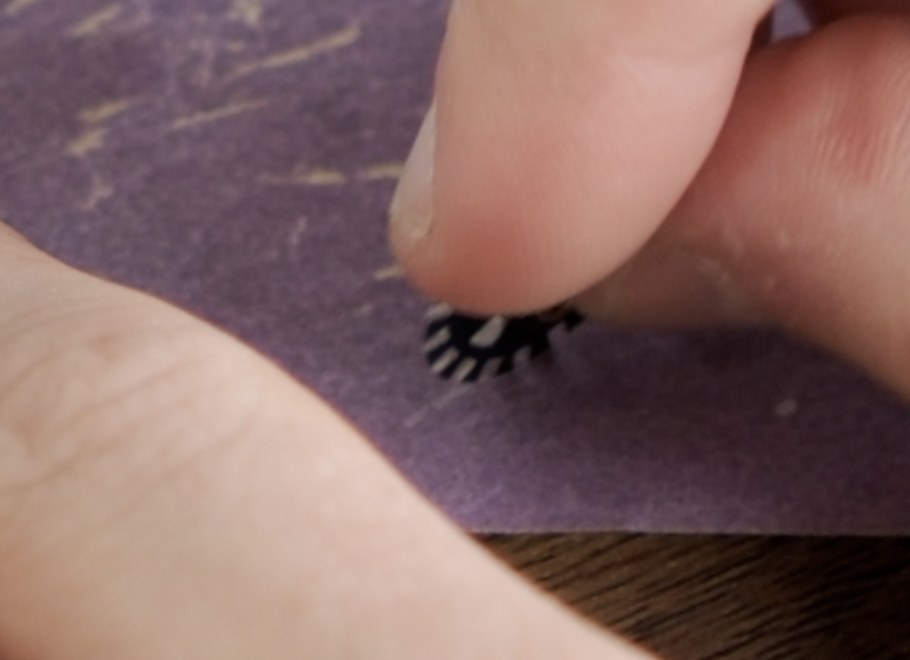Marked tooth on the frame spacing disc being sanded lightly on sandpaper.