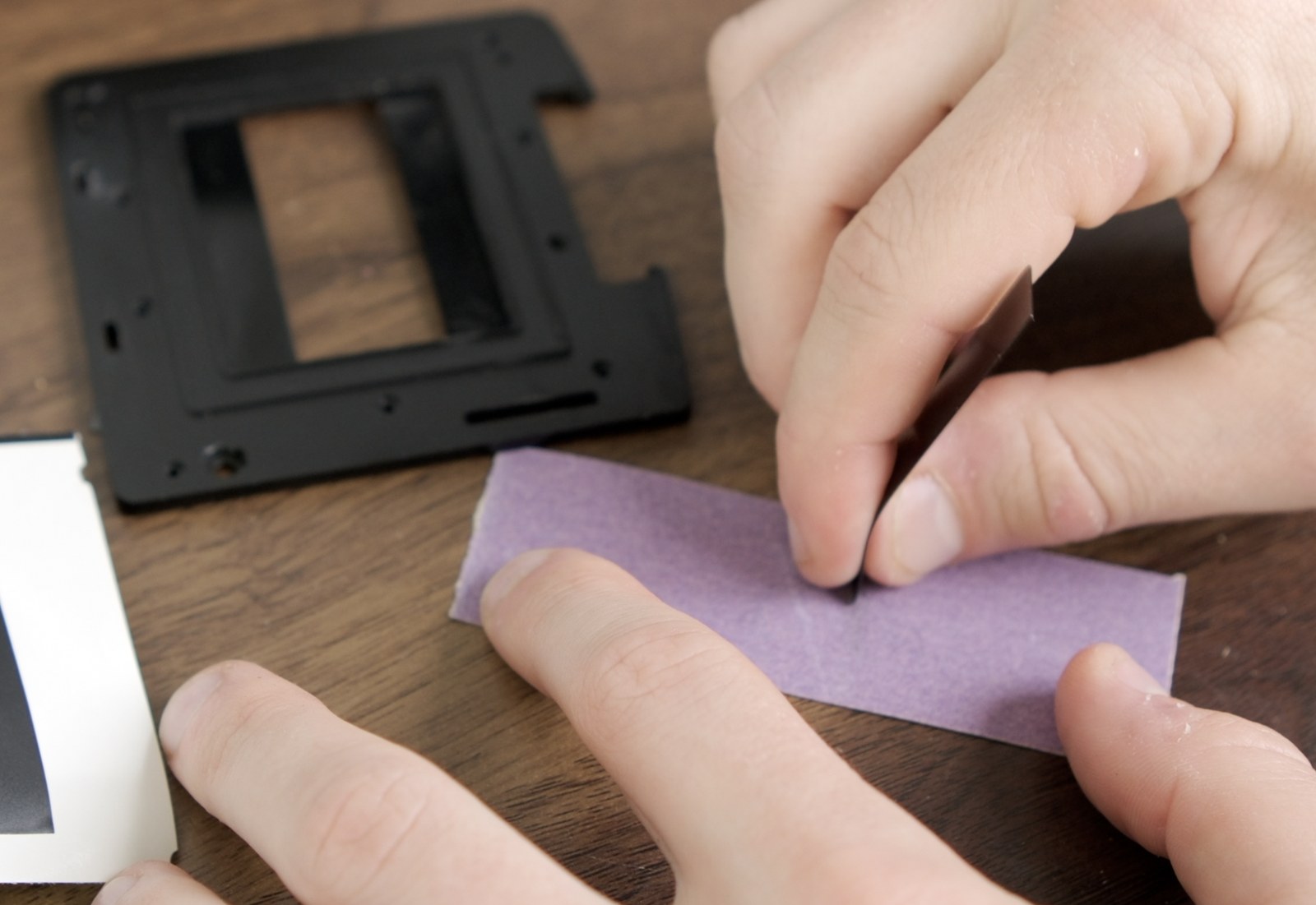Short end of a PET masking strip being sanded on the included sandpaper.