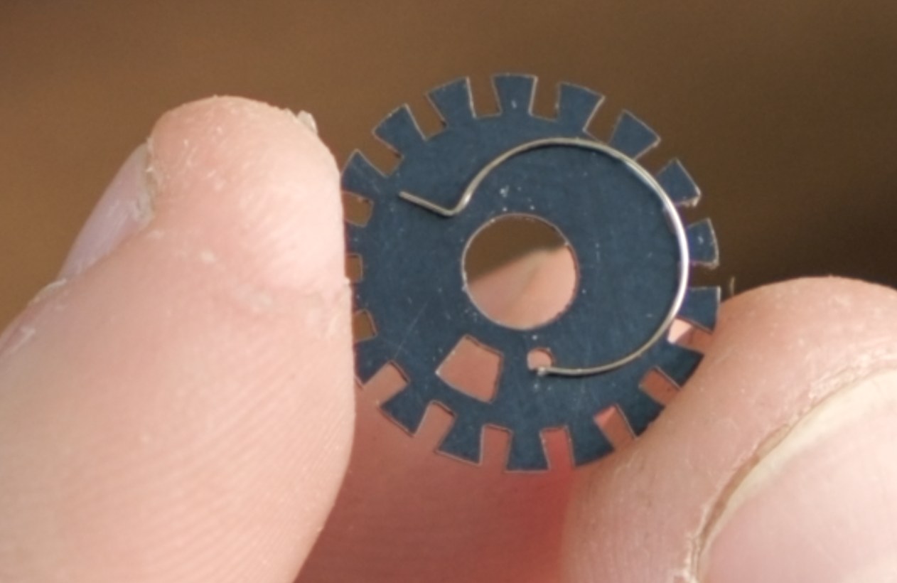 New 18-notch frame spacing disc with the wire coupling spring inserted into the small hole to the right of the arc slot.